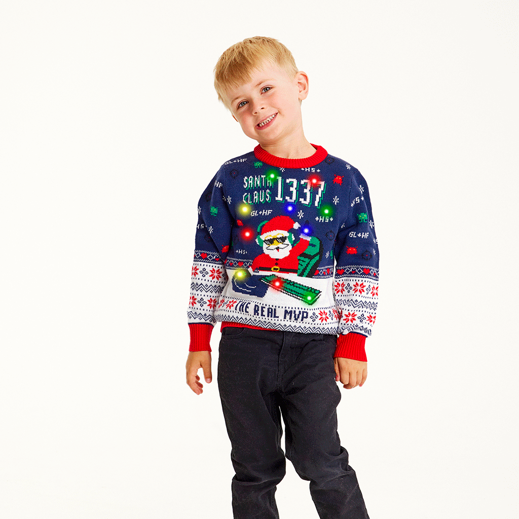 En smilende dreng iført en julesweater med lys på.